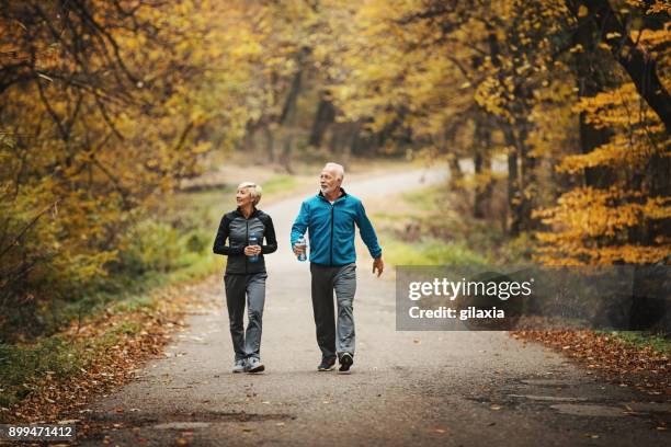 älteres paar powerwalking in einem park. - paar in sportkleidung stock-fotos und bilder