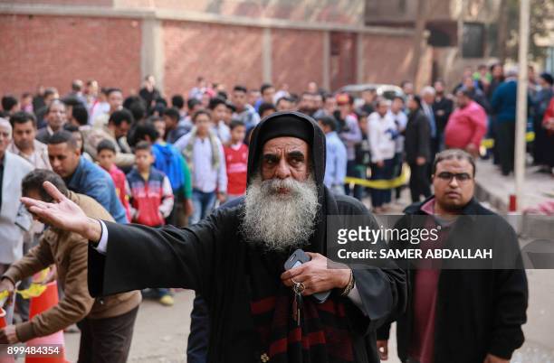 Egyptians are seen gathered at the cordoned off site of a gun attack outside a church south of the capital Cairo, on December 29, 2017. A gunman...