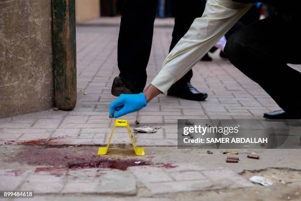 Close up shot shows Egyptian forensic policemen inspecting the site of a gun attack at a church south of the capital Cairo, on December 29, 2017. A...