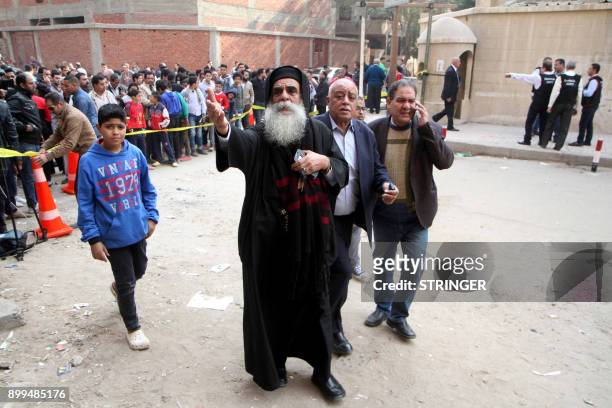 Egyptian onlookers are seen gathered at a cordoned off area following a gun attack outside a church south of the capital Cairo, on December 29, 2017....