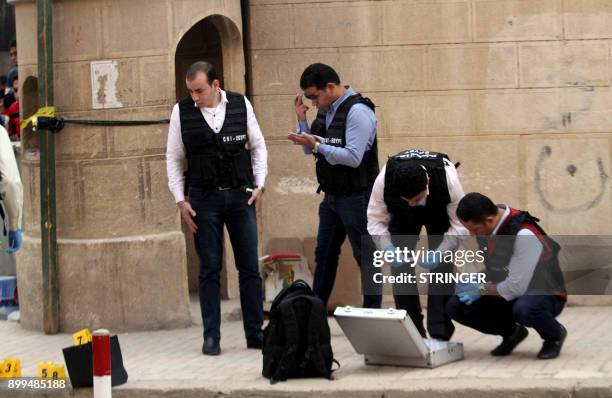 Egyptian security members and forensic police inspect the site of a gun attack outside a church south of the capital Cairo, on December 29, 2017. A...