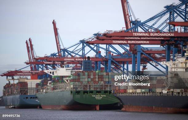 Shipping containers sit on the docked Thalassa Pistis cargo vessel at the Hamburger Hafen und Logistik AG Container Terminal Burchardkai at the Port...