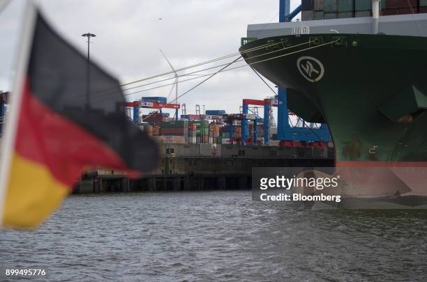 German national flag flies in front of shipping containers as they sit dockside next to the Thalassa Pistis container vessel at the Hamburger Hafen...