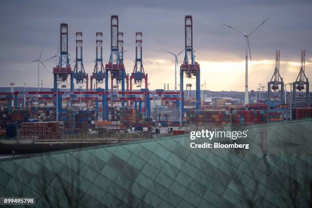 Containers and cranes sit beyond a rooftop at the Hamburger Hafen und Logistik AG Container Terminal Burchardkai in the Port of Hamburg in Hamburg,...