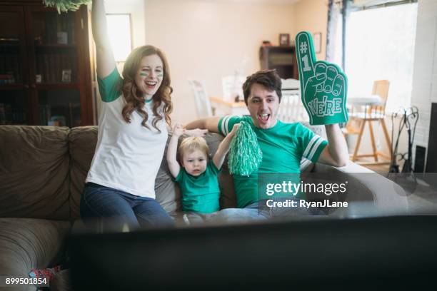 family cheering while watching football game - foam hand stock pictures, royalty-free photos & images