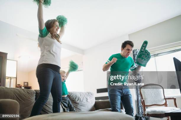 family cheering while watching football game - white pom pom stock pictures, royalty-free photos & images