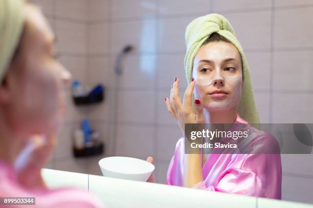 vrouw gezichtsmasker aanbrengend de badkamer - room stockfoto's en -beelden