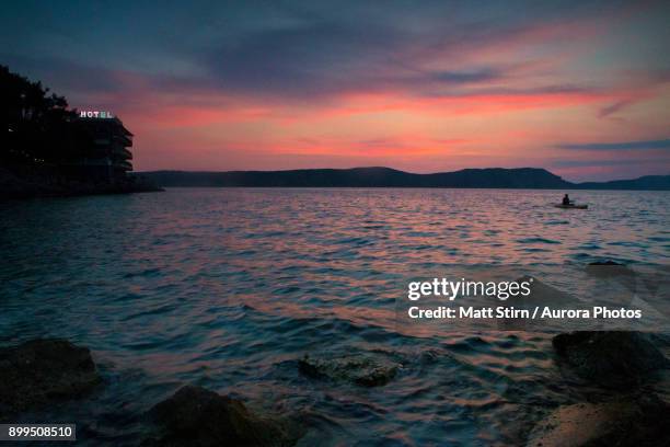 sea kayaker and hotel on coastline at sunset, pylos, messenia, peloponnese, greece - messenia stockfoto's en -beelden