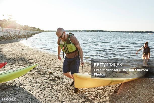 two men carrying kayak on lakeshore, portland, maine, usa - portland maine stock-fotos und bilder