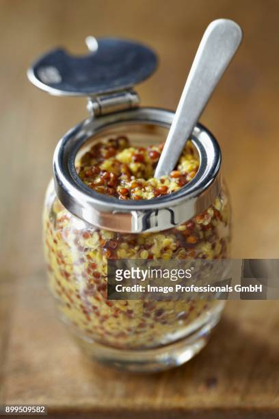 coarse-grained mustard in a jar with a spoon - grainy mustard stockfoto's en -beelden
