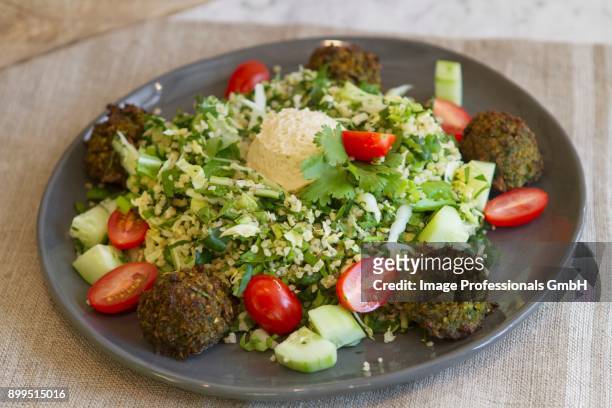 bulgur salad with falafel, hummus, dandelion, kale, chinese cabbage, cucumbers, tomatoes and mint - bohnenkraut stock-fotos und bilder