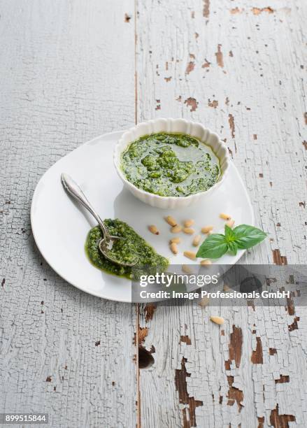 pesto in a white bowl; spilling over the side; spoon - herb sauce stock pictures, royalty-free photos & images