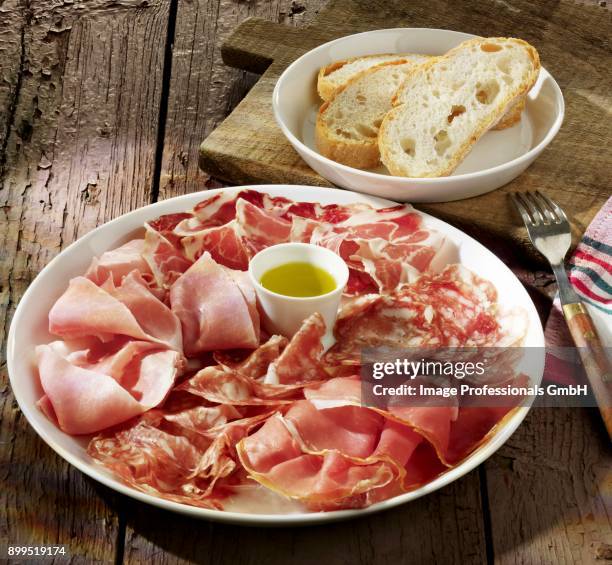 sausage and ham platter with olive oil and white bread - charcutería fotografías e imágenes de stock