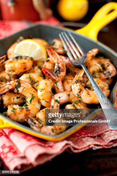 garlic, lemon and parsley shrimp in an iron skillet with a fork - gambas ストックフォトと画像