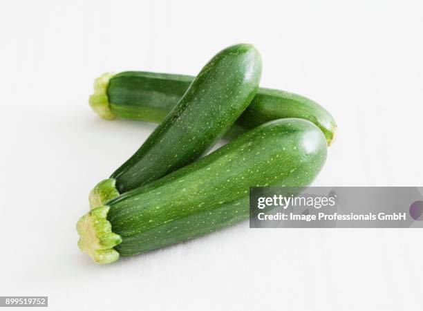 three courgettes against a white background - zucchine stock pictures, royalty-free photos & images