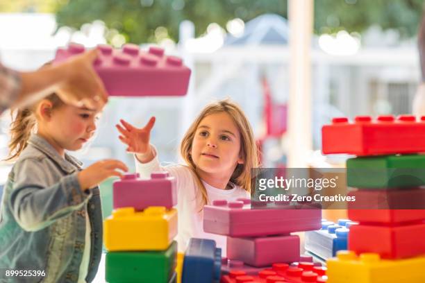 two young children, outdoors, playing with foam building blocks - gemischte altersgruppe stock-fotos und bilder
