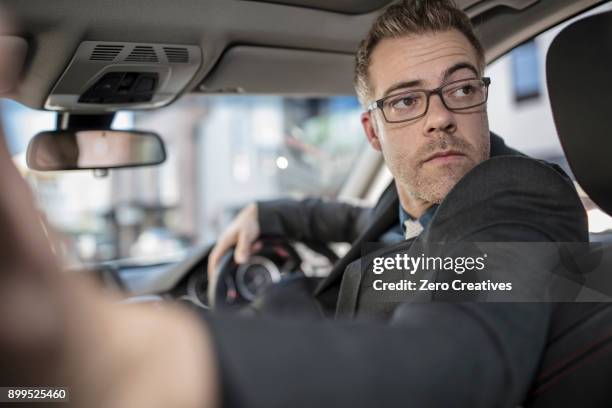 businessman driving car, looking over shoulder, reversing - rückwärts fahren stock-fotos und bilder