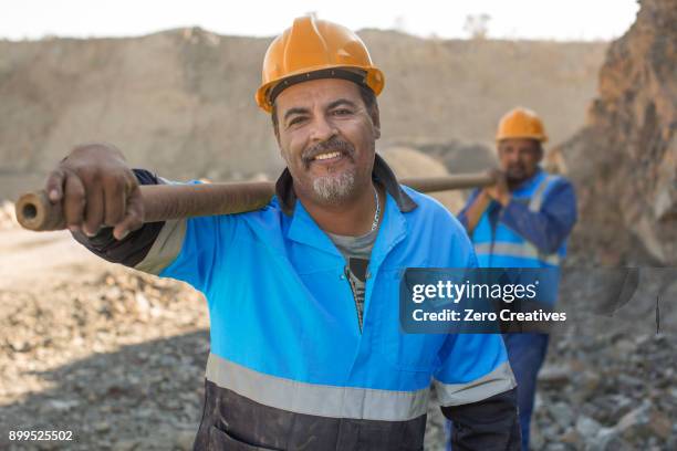 portrait of quarry workers in quarry, carrying metal pipe - miner helmet portrait stock pictures, royalty-free photos & images