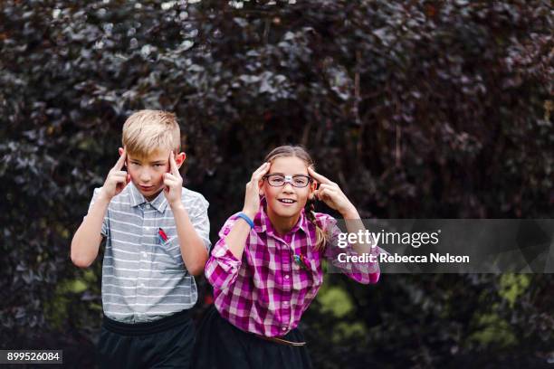 siblings dressed up as nerds, hands on head looking at camera - テレパシー ストックフォトと画像