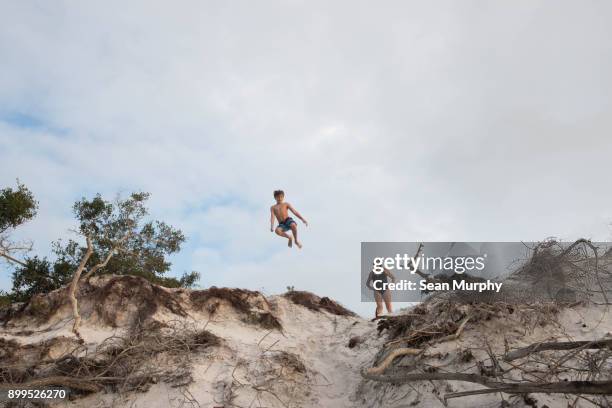 mother and son diving off cliff, destin, florida - festin stock-fotos und bilder