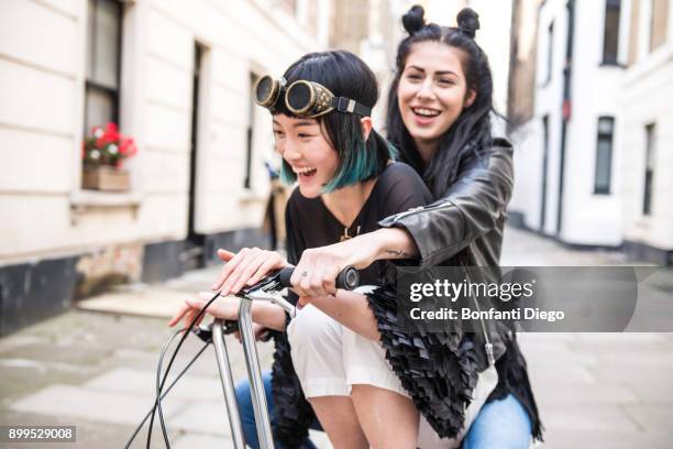 two young stylish women cycling retro bicycle along street - asian cycling stock pictures, royalty-free photos & images