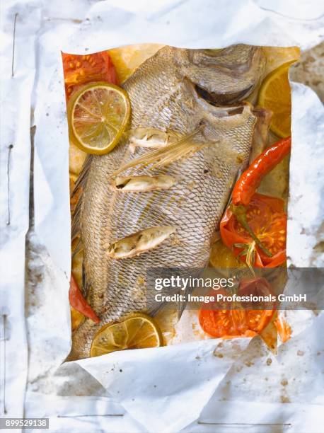 sea bream with lime,tomatoes and pepper cooked in wax paper - orata stock-fotos und bilder