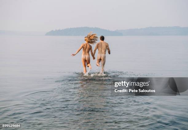 rear view of nude couple running into water - skinny dipping stock pictures, royalty-free photos & images