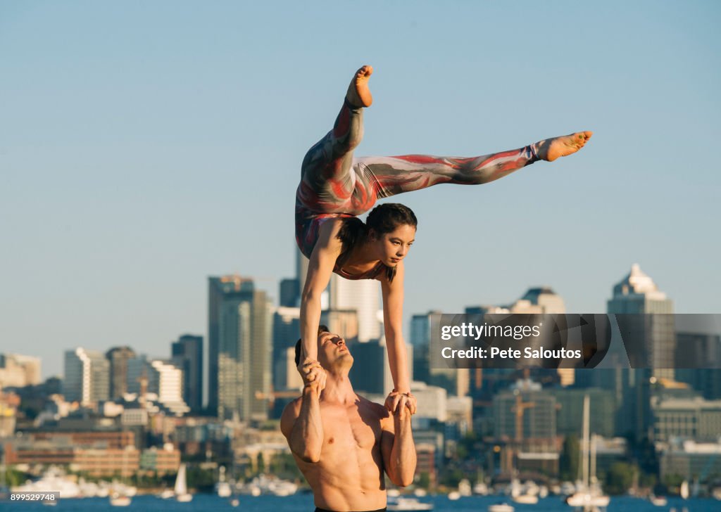 Teenage girl and young man, outdoors, woman balancing on mans hands in yoga position