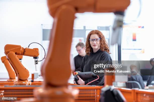 portrait of female robotics apprentice using test industrial robots in robotics facility - progress pride stock pictures, royalty-free photos & images