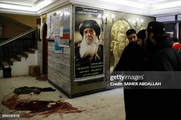 Picture taken on December 29, 2017 shows blood stains on the floor next to a poster of the late Pope Shenouda III of Alexandria following a gun...