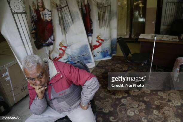 Man sits inside the Mar Mina church while blood-stained cloth can be seen in the background, after a gun attack on the church in Helwan, Southeastern...