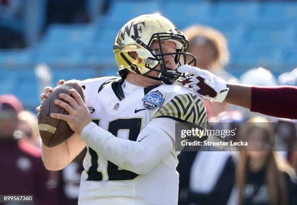 Jayden Peevy of the Texas A&M Aggies grabs the facemask of John Wolford of the Wake Forest Demon Deacons during the Belk Bowl at Bank of America...