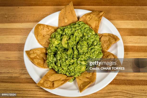 Guacamole and Totopos with different types of chili peppers and peanut sauces are served with traditional "al pastor" tacos made with thin pork...