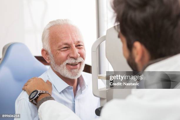 senior patiënt raadpleging met opticien in office - smiling mature eyes stockfoto's en -beelden