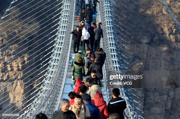 Tourists walk on the glass-bottomed suspension bridge at Hongyagu Scenic Area on December 26, 2017 in Pingshan, Hebei Province of China. The...