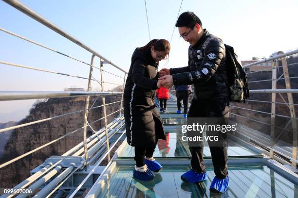 Tourists walk on the glass-bottomed suspension bridge at Hongyagu Scenic Area on December 26, 2017 in Pingshan, Hebei Province of China. The...