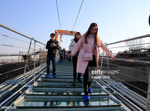 Tourists walk on the glass-bottomed suspension bridge at Hongyagu Scenic Area on December 26, 2017 in Pingshan, Hebei Province of China. The...