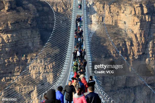 Tourists walk on the glass-bottomed suspension bridge at Hongyagu Scenic Area on December 26, 2017 in Pingshan, Hebei Province of China. The...