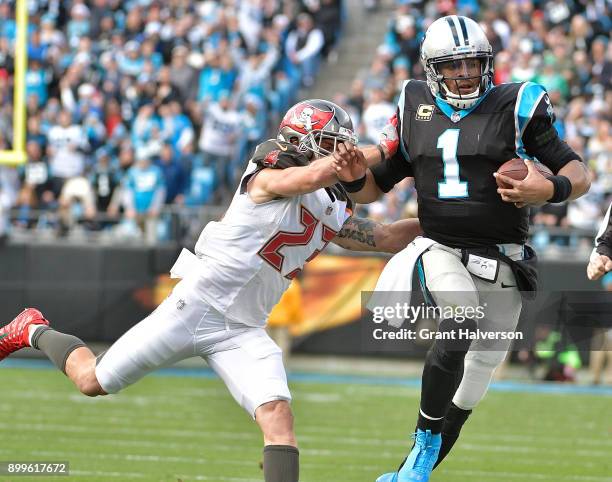 Cam Newton of the Carolina Panthers fends off Chris Conte of the Tampa Bay Buccaneers during their game at Bank of America Stadium on December 24,...