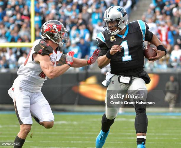 Cam Newton of the Carolina Panthers fends off Chris Conte of the Tampa Bay Buccaneers during their game at Bank of America Stadium on December 24,...