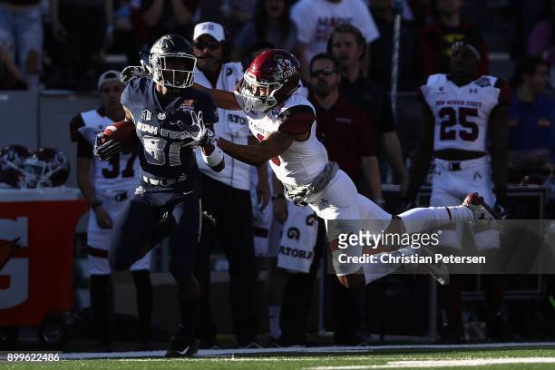 Wide receiver Savon Scarver of the Utah State Aggies returns a kick-off past defensive lineman Stody Bradley of the New Mexico State Aggies for a...