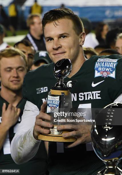 Michigan State Spartans quarterback Brian Lewerke lifts the offensive MVP Trophy on the field after the Spartans defeated the Washington State...