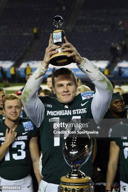 Michigan State Spartans quarterback Brian Lewerke lifts the offensive MVP Trophy on the field after the Spartans defeated the Washington State...