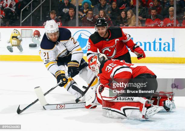 Cory Schneider of the New Jersey Devils makes the first period save on Kyle Okposo of the Buffalo Sabres at the Prudential Center on December 29,...