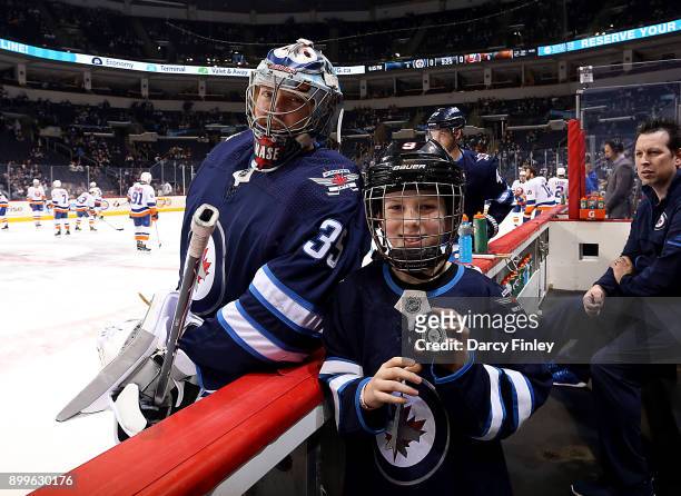 Goaltender Steve Mason of the Winnipeg Jets poses with the Red River Mutual Junior Trainer during the pre-game warm up prior to NHL action against...