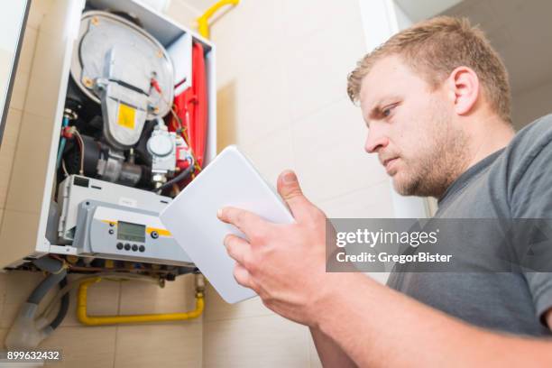 technician repairing gas furnace using digital tablet - gas engineer stock pictures, royalty-free photos & images