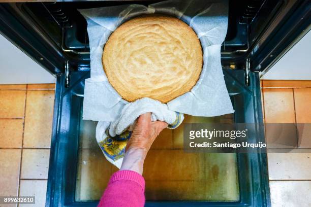 removing a cake from the oven - christmas cake stock pictures, royalty-free photos & images