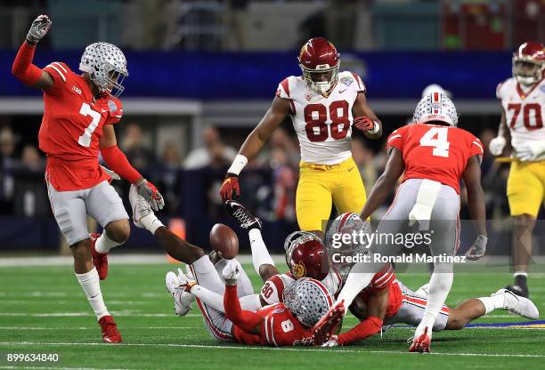 Deontay Burnett of the USC Trojans fumbles the ball while tackled by Damon Arnette and Kendall Sheffield of the Ohio State Buckeyes in the first...