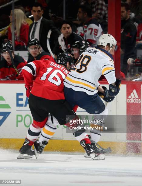Steven Santini of the New Jersey Devils and Zemgus Girgensons of the Buffalo Sabres battle for position during the game at Prudential Center on...