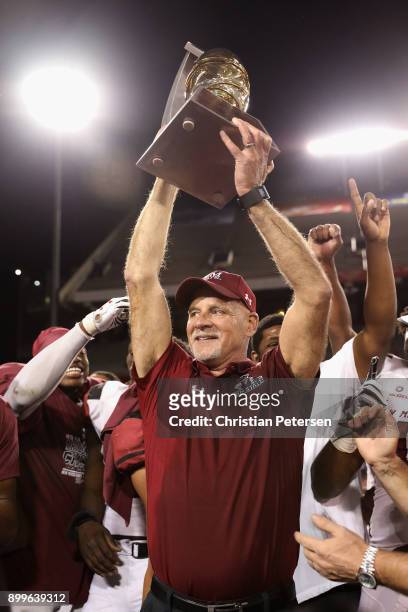 Head Coach Doug Martin of the New Mexico State Aggies holds up the Nova Home Loans Arizona Bowl trophy after defeating the Utah State Aggies at...